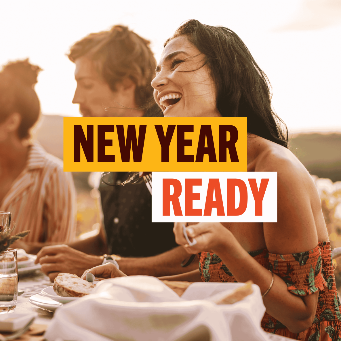 Words New Year Ready with lady laughing in the background at a table of food with friends 